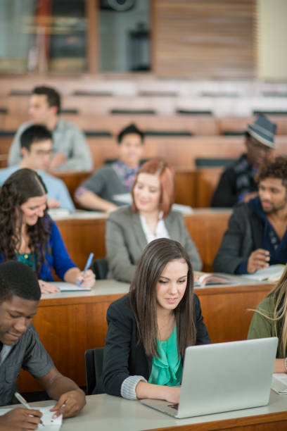 A multi ethnic group of college students seated in a lecture hall.