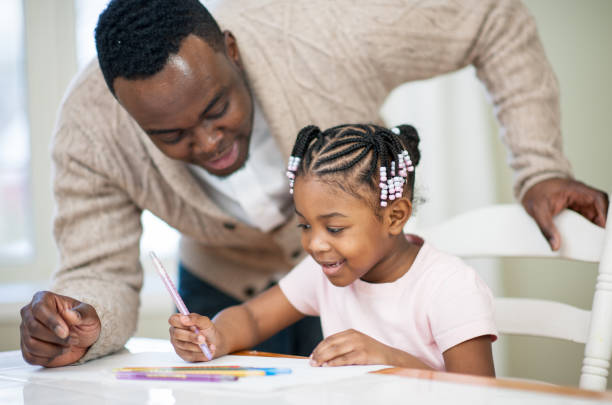 Father and Daughter Stock Photo A father is helping his daughter with her art work at the table at home. literacy photos stock pictures, royalty-free photos & images
