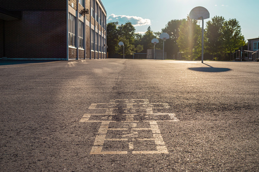 School building and schoolyard in the evening. Hopscotch game on asphalt in the school yard playground.