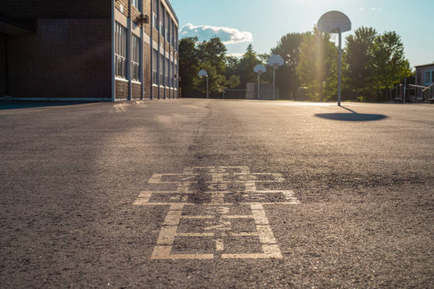 School building and school yard in the evening School building and schoolyard in the evening. Hopscotch game on asphalt in the school yard playground. schoolyard stock pictures, royalty-free photos & images