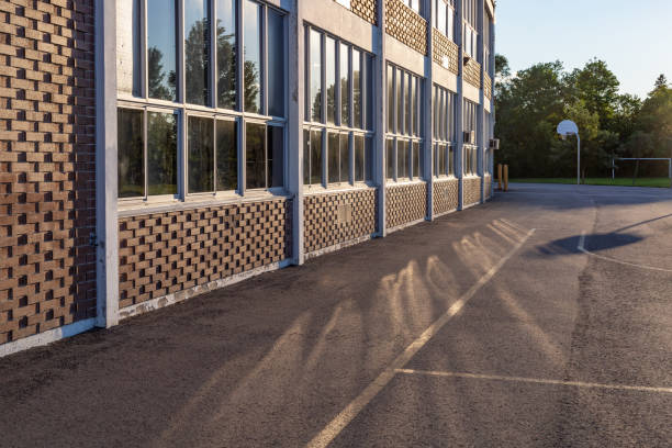 bâtiment d’école et cour d’école dans la soirée - schoolyard photos et images de collection