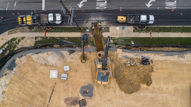 Excavator working on the construction site at the first stage of the earthwork, nearby a road. Construction site. The top view, directly above "bird's eye" aerial view. earthwork stock pictures, royalty-free photos & images