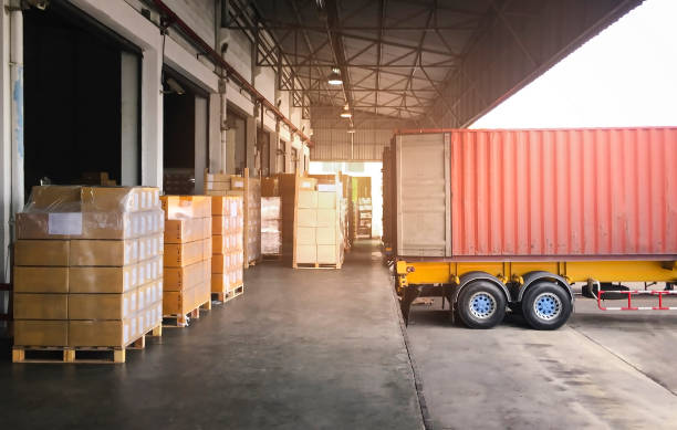 istock Cargo Container Truck Parked Loading at Dock Warehouse. Stacked of Package Boxes on Pallet Rack. Cargo Shipment. Industry Freight Truck Transportation. Shipping Warehousing Logistics. 1305744308