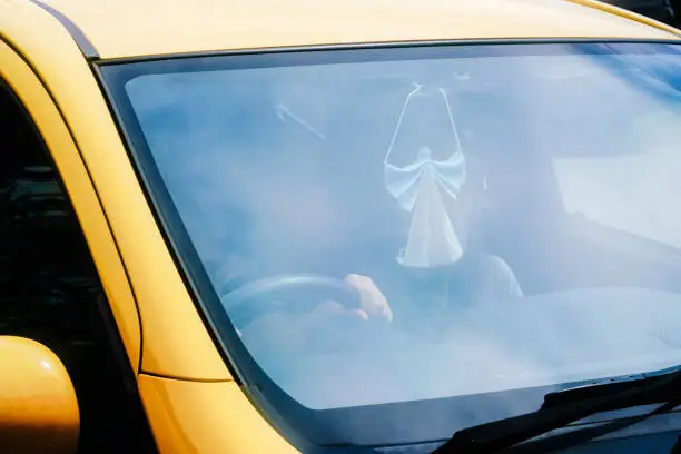 Angel made from protective face mask hanging on rearview mirror of a car