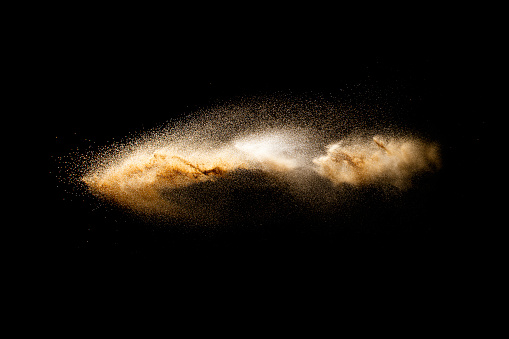 Sand flying explosion isolated on black background. Freeze motion of sandy dust splash.