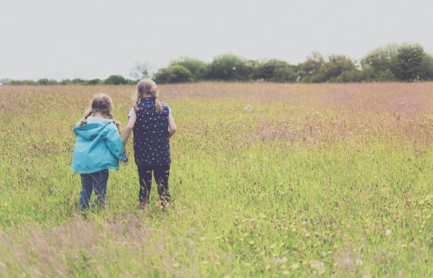 istock Two little girls walking through an open field 1305753134