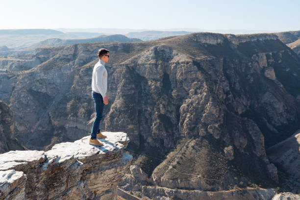 istock Courageous guy stands on dangerous cliff edge in autumn 1305760877