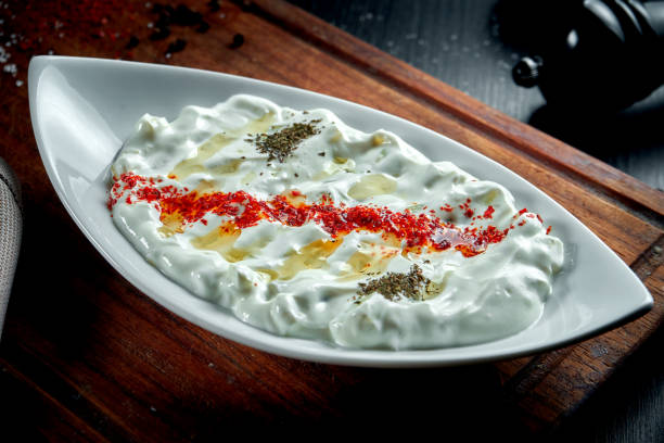 istock Tzatziki, cack, or tarator is a traditional Turkish and Greek appetizer made from fresh yoghurt, cucumbers, spices and olive oil in a white plate. Dark background 1305761077