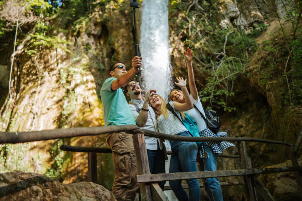 istock Young hikers taking selfie in front of small mountain waterfall 1305762757