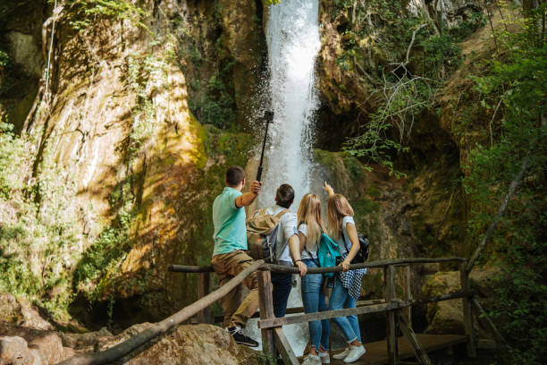 istock Young hikers taking selfie in front of small mountain waterfall 1305762815