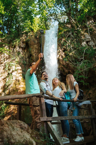 istock Young hikers taking selfie in front of small mountain waterfall 1305762838