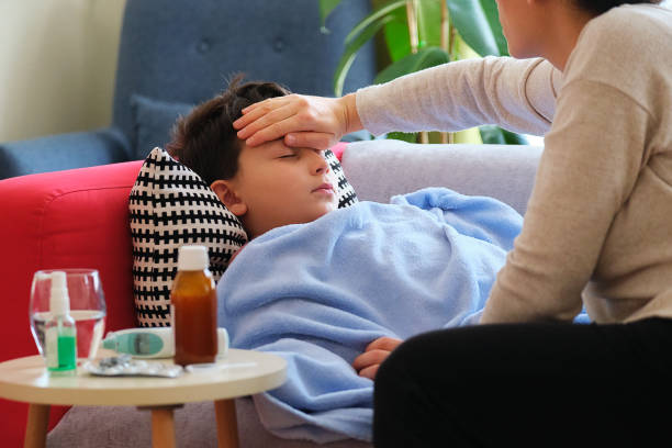 istock Sick boy lying down on sofa at home. He is together with his mother 1305765257