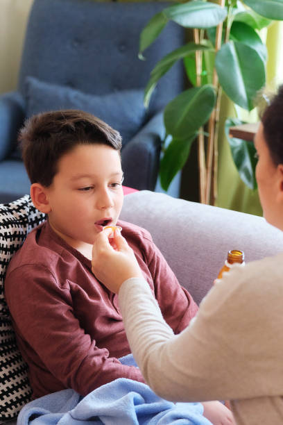 istock Sick boy lying down on sofa at home. He is together with his mother 1305765270
