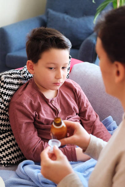 istock Sick boy lying down on sofa at home. He is together with his mother 1305765804