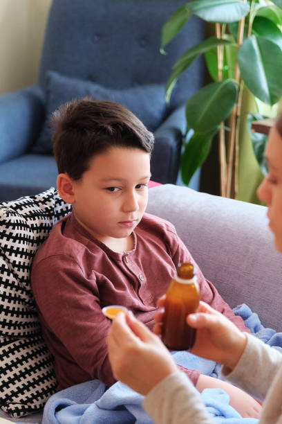 istock Sick boy lying down on sofa at home. He is together with his mother 1305765831