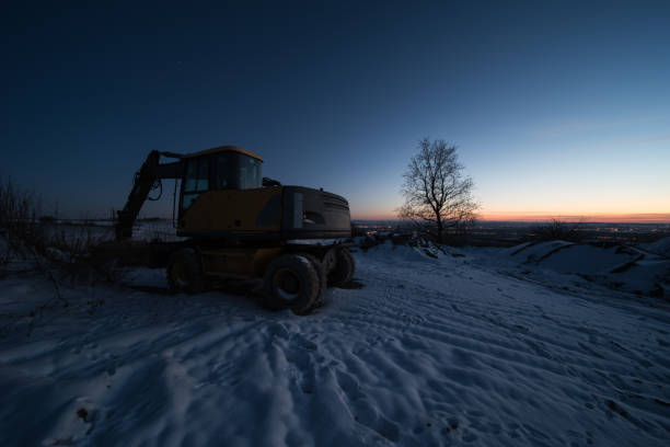 bagger in blue hour an excavator in the blue hour, the picture was taken in winter in southern germany. bagger stock pictures, royalty-free photos & images