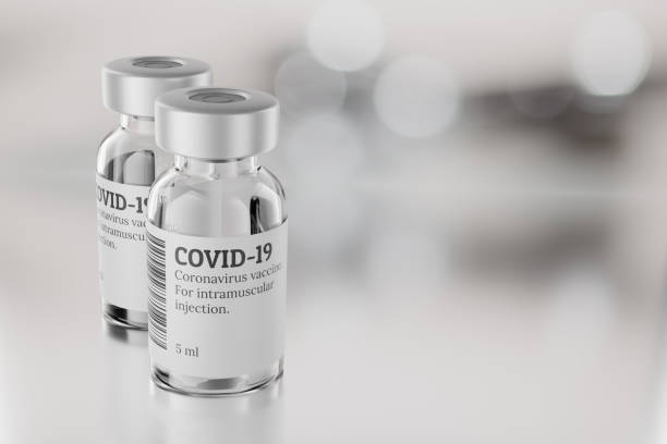 istock COVID-19 vaccine vials on gray blur background. 3d rendering illustration. 1305766409