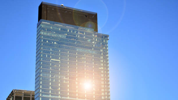istock Modern architecture with sun ray. Glass facade on a bright sunny day with sunbeams on the blue sky. 1305771596
