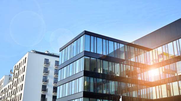 istock Modern architecture with sun ray. Glass facade on a bright sunny day with sunbeams on the blue sky. 1305771640