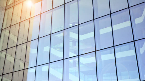 istock Modern architecture with sun ray. Glass facade on a bright sunny day with sunbeams on the blue sky. 1305771782