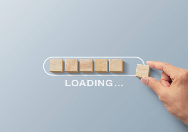 Loading, reboot, refresh or mindset concept. Hand putting wooden blocks in progress bar on gray background with the word LOADING. stock photo