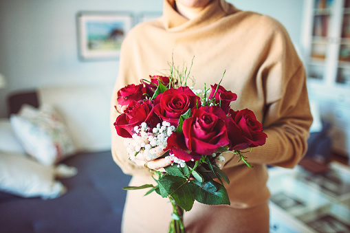 Woman is holding red roses.