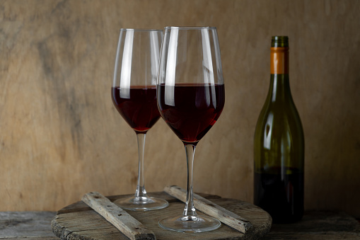 Two glasses of red wine. The bottle of wine is on the table. Wine background. Still life. Alcoholic drink in a glass. Wooden background.