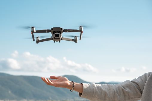 Kavala, Greece - June 6, 2019: Man flying a drone DJI Mavic 2 Pro outdoors. Close up shot of hand and drone in mid air.