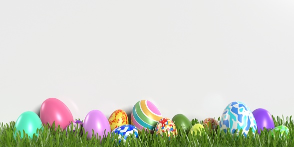 Cute decorated Easter eggs are against white background on green grasses. Easy to crop for all social media and print design sizes.