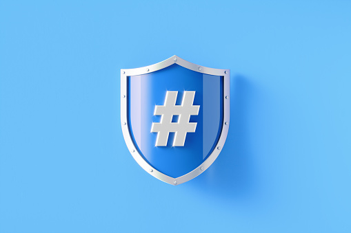 Silver shield with hashtag symbol sitting on blue background, Horizontal composition with copy space. Online messaging and safety concept.