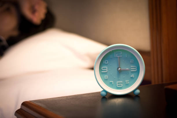 istock Insomnia or Sleep changes and disorders in elderly concept.Alarm clock time at 2 a.m. morning with blurry women lay down awake. 1305783894
