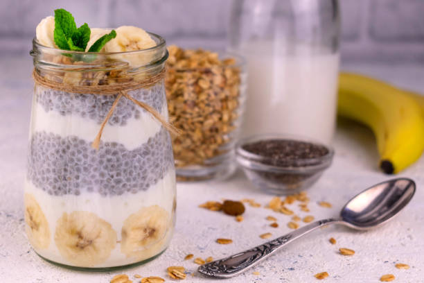 istock Chia pudding with banana and granola in a jar on a white background. Close-up. 1305783954