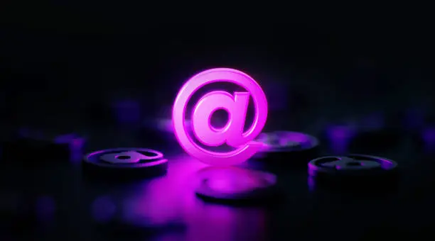 Photo of E-Mail And Communication Concept - At Symbol Glowing Amid Black At Symbols On Black Background