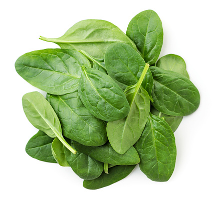 A pile of spinach leaves close-up on a white background. Top view.