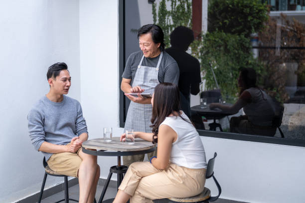 istock Waiter serving couple at a Cafe 1305788561