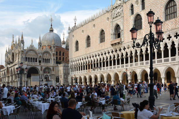 Cafe with people on the San Marco square of Venice bevor the Basilica and the Doges palace - Italy.