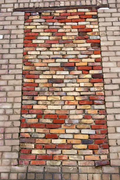 A bricked-up window opening in the brick wall of an old industrial building. Close-up