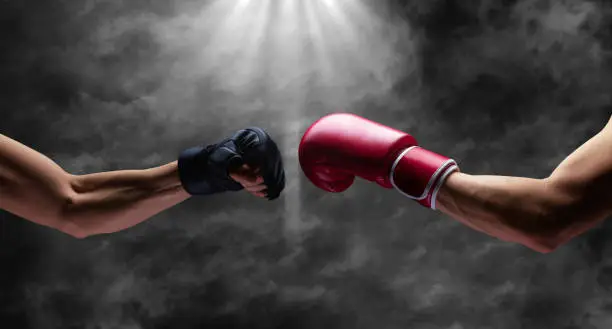 Photo of Boxing and mma fight, close up of two fists hitting each other over dark, dramatic sky with copy space.