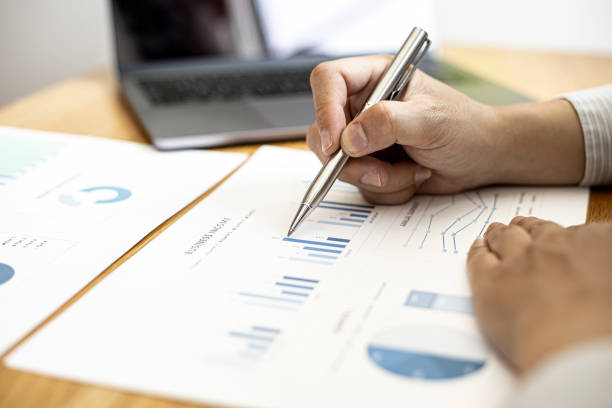 istock A businessman is analyzing the company's financial data from the documents provided by the Finance Department, he examines the data and analyzes and plans for more growth. Financial concept. 1305792235