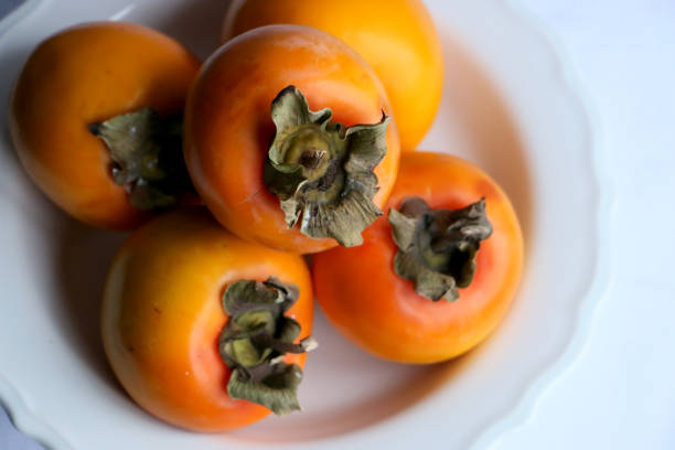 istock Fresh Ripe Persimmons on a White Classic Design Plate, Paradise Palms 1305795778