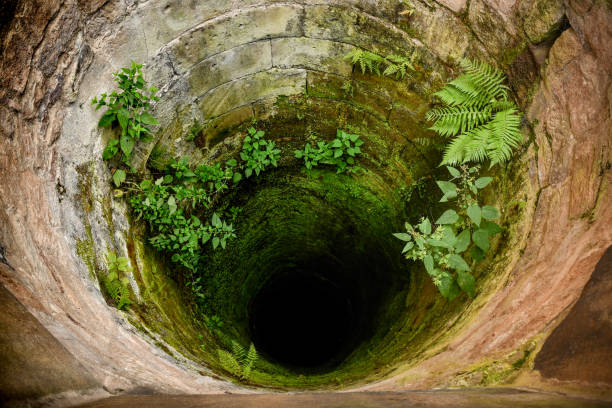 istock A well built of stone, deep and dry, covered with moss. 1305797708