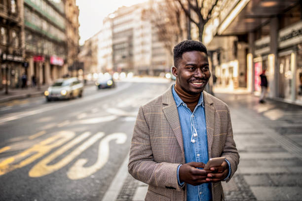 istock Young businessman texting on phone while standing on city street. 1305798277