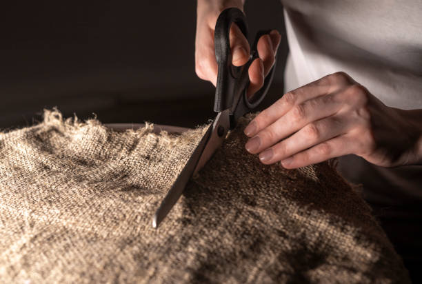 female hands of tailor at work, cutting natural organic linen fabric with sewing scissors - manual worker sewing women tailor imagens e fotografias de stock