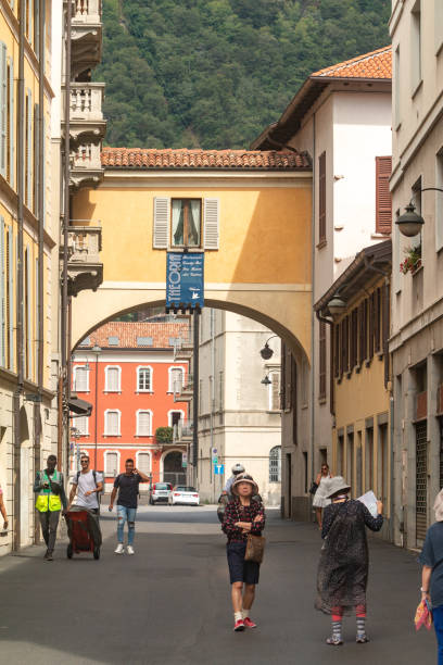 People walking along the streets of Como on Lake Como in Lombardy, Italy. Commercial names can be seen in the background.