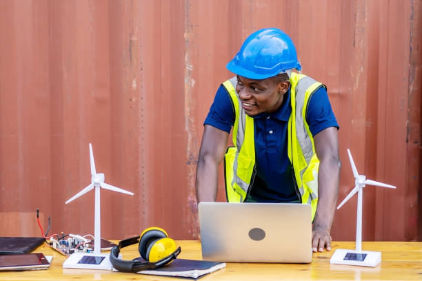 istock Ecology engineer typing on laptop and working on project. On desk are windmill models. Sustainable development concept 1305807085