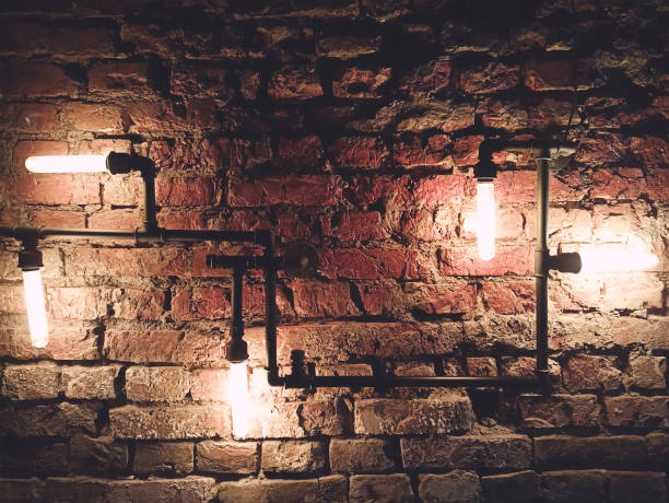 istock Interior design of vintage wall. Rustic design, brick wall with light bulbs and pipes, low lit bar interior 1305807261