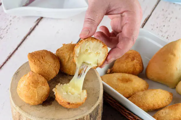 Photo of Savory Brazilians stuffed with melted mozzarella cheese. Served on a wooden log.