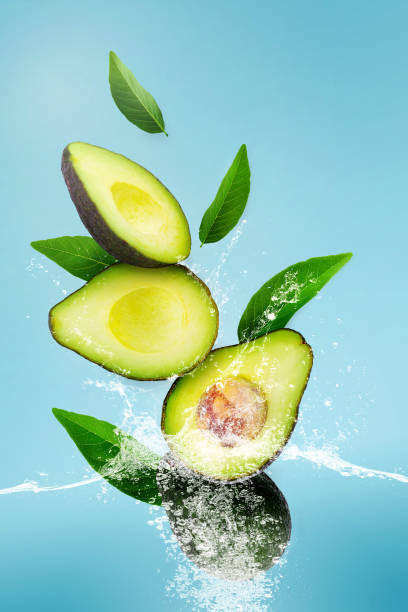 istock Water Splashing on Green Ripe Avocado over Blue Sky Background. 1305808651