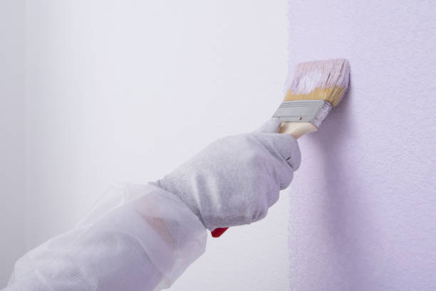 istock on the background of a painted wall, a worker's hand with a brush, close-up 1305811077