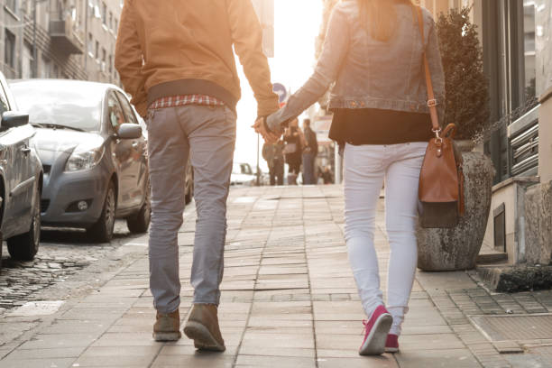 istock Couple holding hands and walking on a sidewalk. 1305815124
